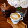 cappuccino v šálke EBENICA COFFEE na stole s kvetmi